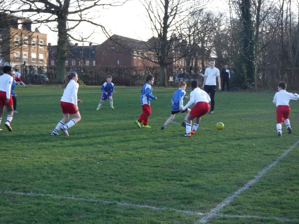 Students are pictured playing a game of Football on the grass during a PE lesson.