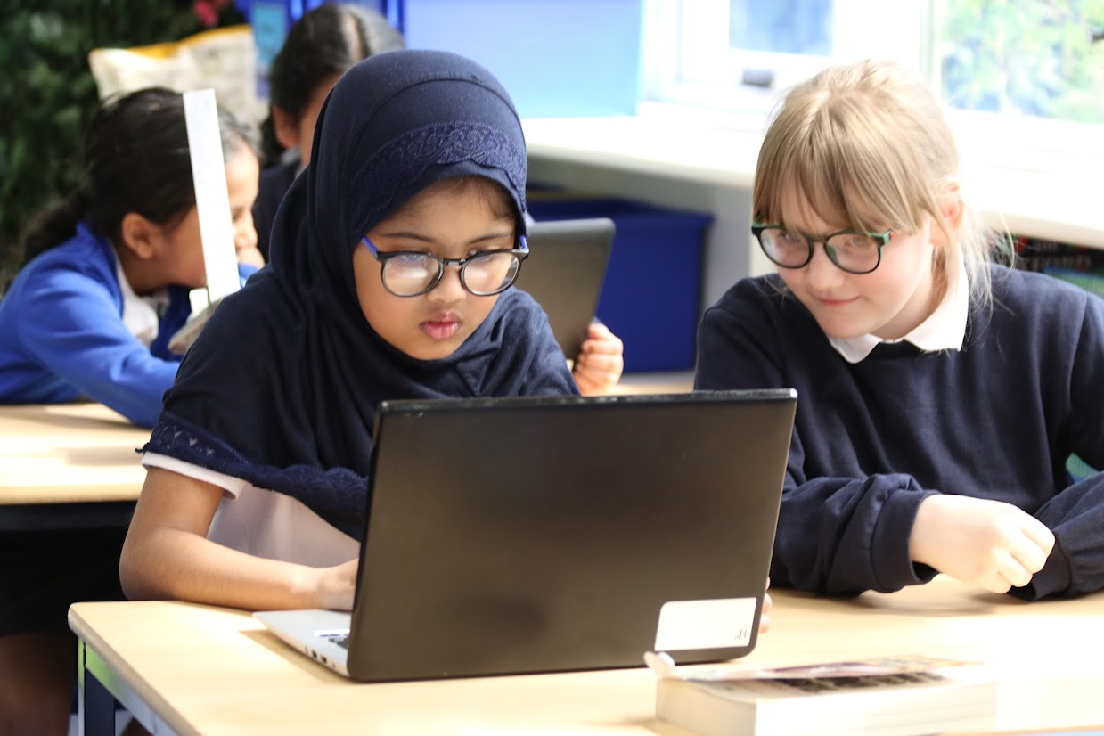 Two students using a laptop during learning time.